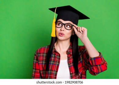 Portrait of attractive minded girl wearing master's cap touching specs copy space isolated over bright green color background - Powered by Shutterstock