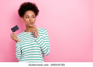 Portrait of attractive minded sly girl holding bank card thinking deciding copy space ad isolated over pink pastel color background - Powered by Shutterstock