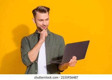 Portrait of attractive minded smart guy using laptop deciding order eshop booking isolated over bright yellow color background