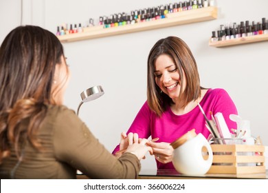 Portrait Of An Attractive Nail Salon Worker Giving A Manicure To One Of Her Regular Customers