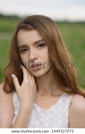 Portrait of an attractive with natural beauty Caucasian redhead young woman in a dress during a walk in the park on a warm summer day. Beauty, fashion, youth, lifestyle.