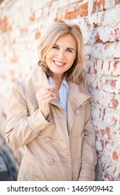 
Portrait Of An Attractive Older Woman With Sympathetic Smile Outside In Trench Coat 