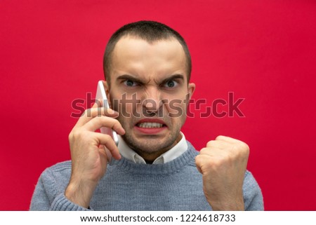 Portrait, attractive, overwrought guy, man talking on phone, looking at the camera, front view, bright red background, close up