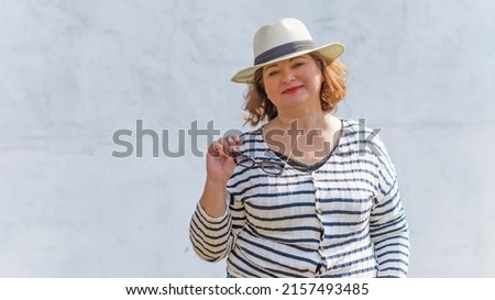 Portrait of attractive plus size mature woman in casual style walk at city at good sunny day and thinking about something. Life of women after 40-50 years