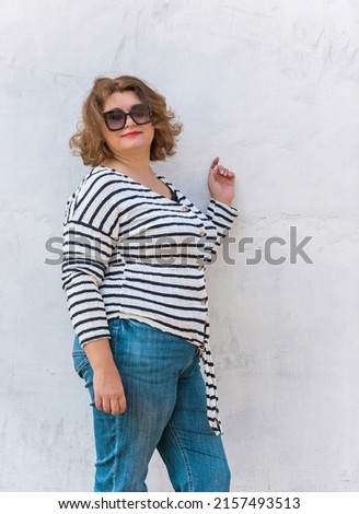 Portrait of attractive plus size mature woman in casual style walk at city at good sunny day and thinking about something. Life of women after 40-50 years