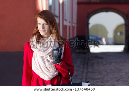 portrait of attractive redhaired girl walking in old town of Tallinn