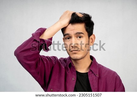 a portrait of an attractive sad Asian man looking at camera while he is disorderly  fraught , messy , muddy and  turbulent , as if something wrong happened , not knowing what to do  bad feeling