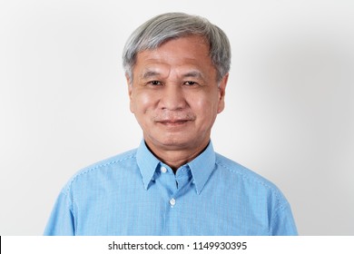 Portrait Of Attractive Senior Asian Man Smiling And Looking At Camera In Studio With White Isolated Background Feeling Positive Grandpa. Headshot Of Mature Older Chinese Man Or Father Concept.