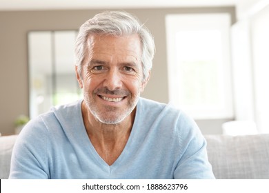Porträt eines attraktiven Senioren mit blauem Pullover entspannend zu Hause