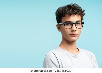 Portrait of attractive serious guy wearing eyeglasses looking at camera isolated on blue background, copy space. Concept of advertisement, vision