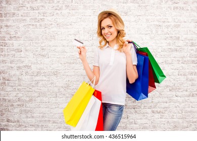 Portrait of attractive shopper holding bank card and packs with clothes