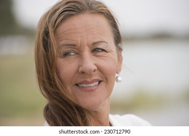 Portrait attractive single mature woman outdoor looking confident happy and relaxed smiling, with bright blurred background and copy space.