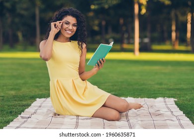 Portrait Of Attractive Smart Cheerful Girl Sitting On Duvet Reading Interesting Book Free Time Studying On Fresh Air Outdoor