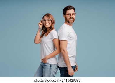 Portrait of attractive smiling man and woman wearing white t shirt and stylish eyeglasses isolated on blue background. Happy confident fashion models posing for pictures in studio  - Powered by Shutterstock