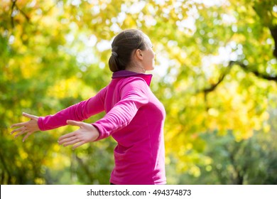 Portrait of an attractive smiling woman outdoors in a sportswear, her hands outstreched. Indian summer. Concept photo, side view