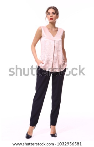 portrait of an attractive student girl in party pink sleeveless blouse black trousers and high heels stiletto black shoes