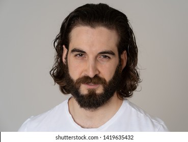 Portrait of Attractive stylish fashion man in his 20s looking sexy with beard, long dark hair and brown eyes. Masculine hipster model posing against neutral background. In People and Beauty concept.