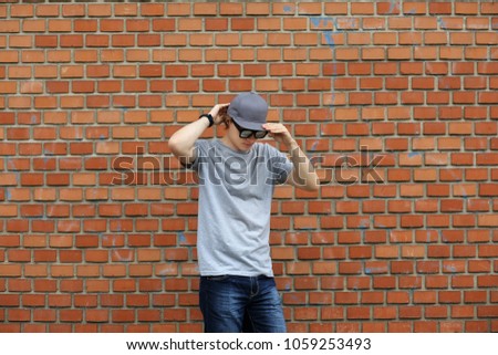 Portrait of attractive teenage boy standing  in front of a brick wall.