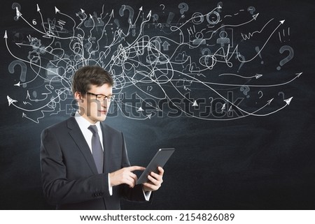 Portrait of attractive thoughtful young european businessman with mobile phone standing on chalkboardblackboard wall background with arrows mesh sketch. Confusion and question concept