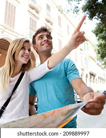 Portrait of an attractive tourist young couple relaxing sightseeing and visiting a destination city on holiday, pointing up and enjoying traveling together, outdoors. Tourism, travel and lifestyle.
