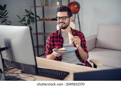 Portrait of attractive trendy cheerful guy eating fresh homemade snack watching web tv at office work place station indoor