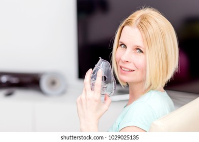The portrait of an attractive woman heals herself with an inhaler.