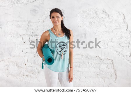 Portrait of attractive woman holding green yoga or fitness mat after working out at home or in club. Friendly smiling sport instructor looking at camera. Healthy life concept. horizontal shot
