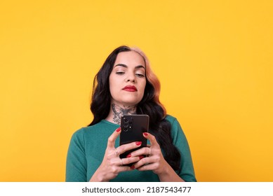 Portrait Of An Attractive Woman Using Smart Phone Over Yellow Background. Studio Shot.