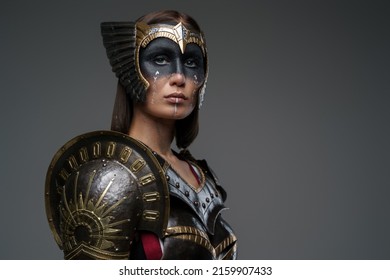 Portrait of attractive woman warrior with painted face dressed in dark steel armor.