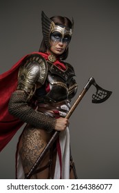 Portrait Of Attractive Woman Warrior With Tattoos And Painted Face Holding Axe.