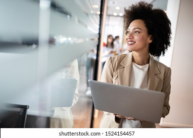 Portrait of an attractive young african businesswoman smiling while standing by windows in office