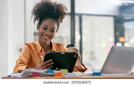 Portrait of an attractive young african businesswoman smiling while using tablet and relaxing during work at office. - Powered by Shutterstock