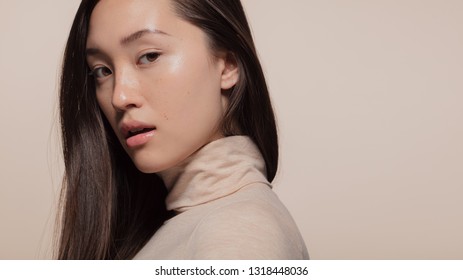 Portrait Of Attractive Young Asian Woman With Brown Hair Against Beige Background. Korean Female Model Looking At Camera.