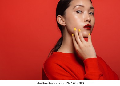 Portrait of attractive young asian woman with beautiful make up on red background. Asian female model with red top and lipstick.