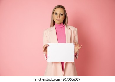 Portrait of attractive young blonde hair woman 30-35 years old holding blank of paper A4 for sign on pink background. businesswoman is wearing pink jacket. Top manager, female blog - Powered by Shutterstock