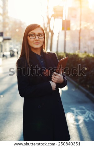 Portrait of an attractive young businesswoman holding a digital tablet while standing outdoors, diplomatic and confident woman