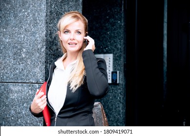 Portrait Of An Attractive Young Businesswoman Using Mobile Phone In The Office Building Entrance 