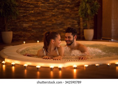 Portrait of an attractive young couple relaxing in a jacuzzi. High ISO image, ambiental light only.