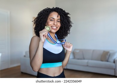 Portrait of an attractive young female athlete posing with her gold medal. African American Athlete showing first place medal - Powered by Shutterstock