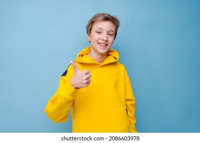 Portrait of attractive young guy showing different hand gestures on blank advertising space in yellow sweatshirt, isolated on blue colored background - Powered by Shutterstock