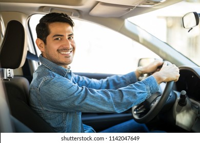 Portrait Of Attractive Young Hispanic Man Sitting In The Driving Seat Of His Car And Making An Eye Contact