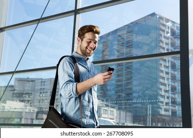 Portrait Of An Attractive Young Man Walking And Looking At Mobile Phone