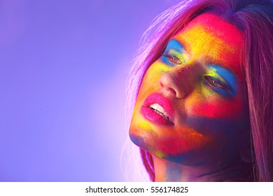 Portrait of attractive young woman with bright facial body-art on purple background