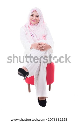 portrait of attractive young woman with hijab smiling to camera while sitting on couch