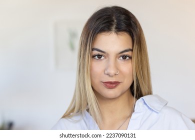 Portrait of attractive young woman in office. Confident Latin woman with nose ring wearing casual shirt looking at camera. Office worker concept - Powered by Shutterstock