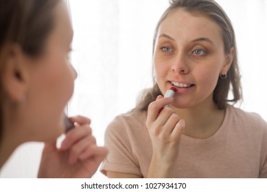 Portrait of attractive young woman putting on makeup
