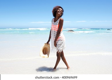 Portrait of attractive young woman walking in water by beach  