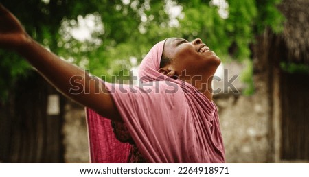 Portrait of Authentic African Woman Enjoying the Blessing of Falling Rain. Female From a Rural Village Standing Under the Rain with a Blurry Greenery Background and Feeling Refreshed by Water