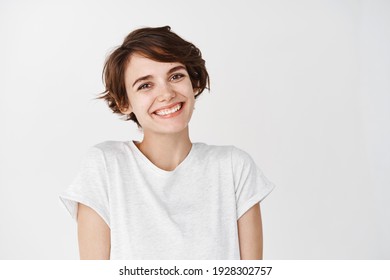 Portrait von authentischer glücklicher Frau ohne Make-up, lächeln bei der Kamera, stehend süß auf weißem Hintergrund.