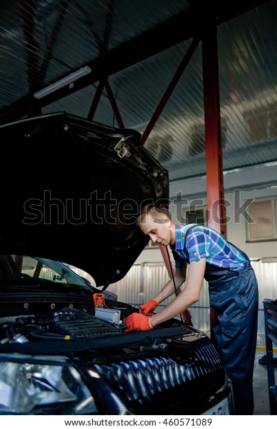 Portrait of an auto mechanic at work on a car in\
his garage